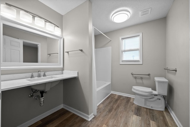 full bathroom featuring toilet, wood finished floors, visible vents, a sink, and shower / washtub combination