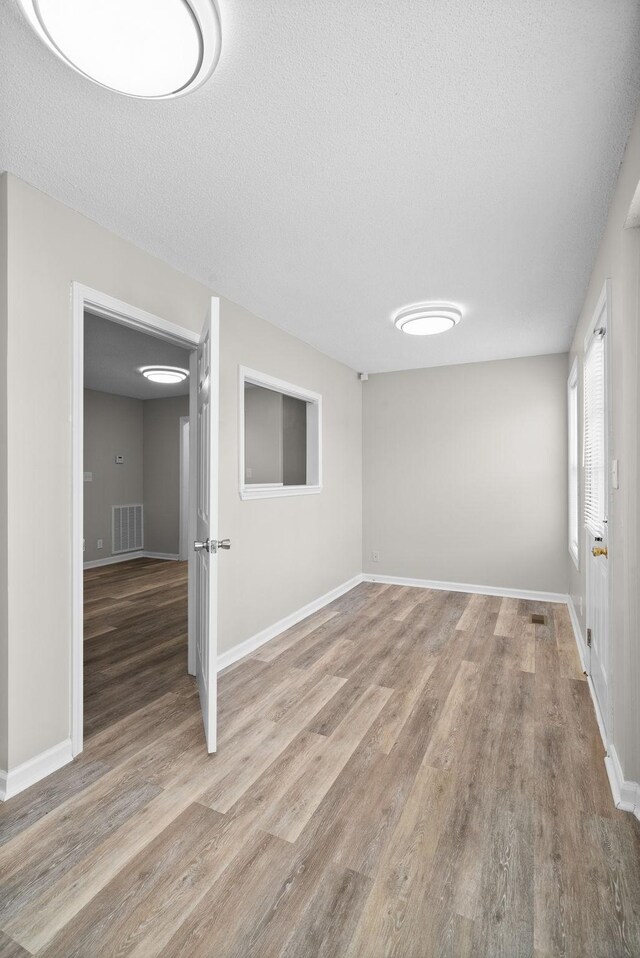 unfurnished room featuring a textured ceiling, visible vents, and wood finished floors