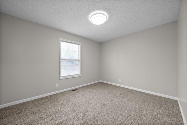 unfurnished room with baseboards, visible vents, a textured ceiling, and carpet flooring