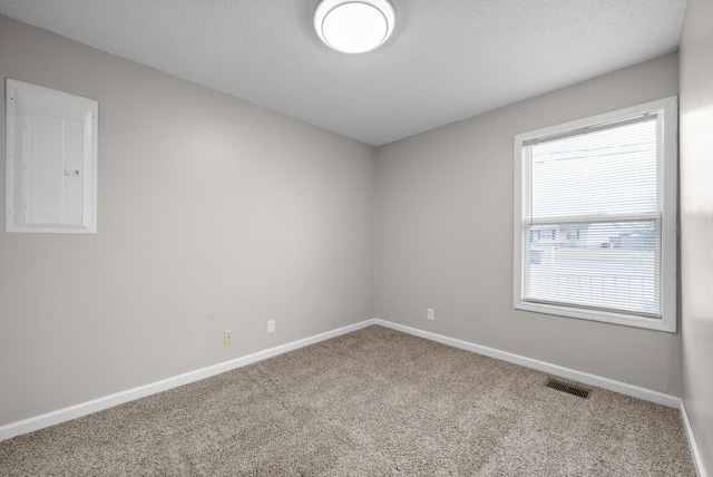 empty room with visible vents, carpet flooring, electric panel, and baseboards