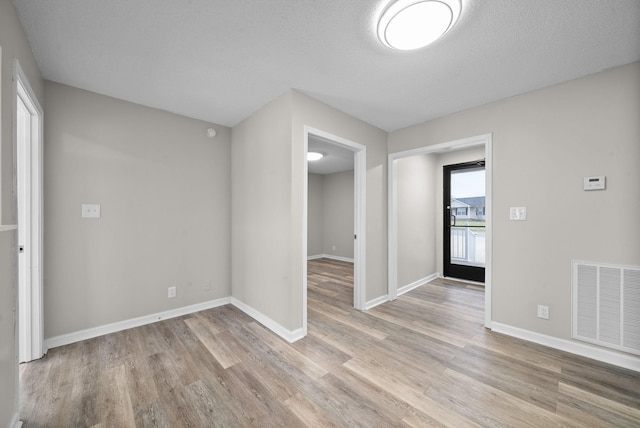 empty room featuring light wood-style floors, baseboards, and visible vents