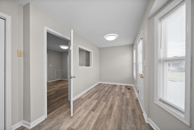 empty room featuring light wood finished floors, baseboards, and visible vents