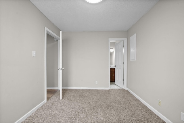 unfurnished bedroom with carpet, a textured ceiling, and baseboards