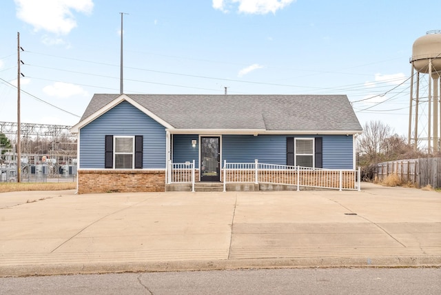 view of front of home featuring covered porch, brick siding, and roof with shingles