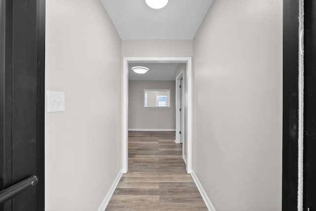 corridor with light wood-type flooring and baseboards