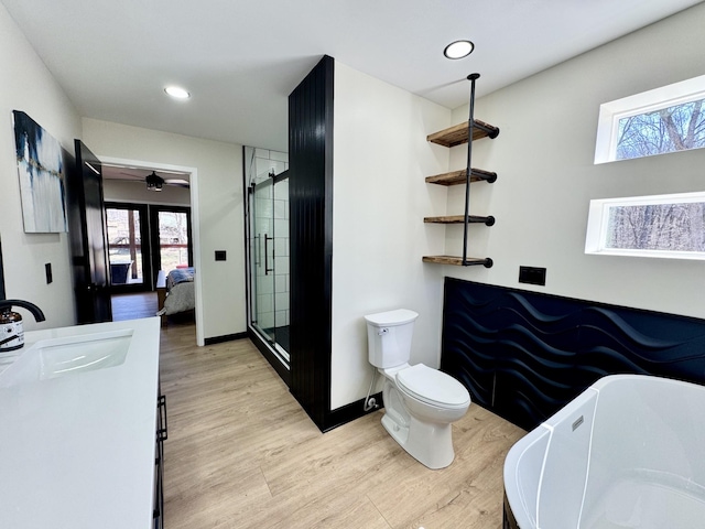 ensuite bathroom with plenty of natural light, a freestanding bath, a sink, and wood finished floors