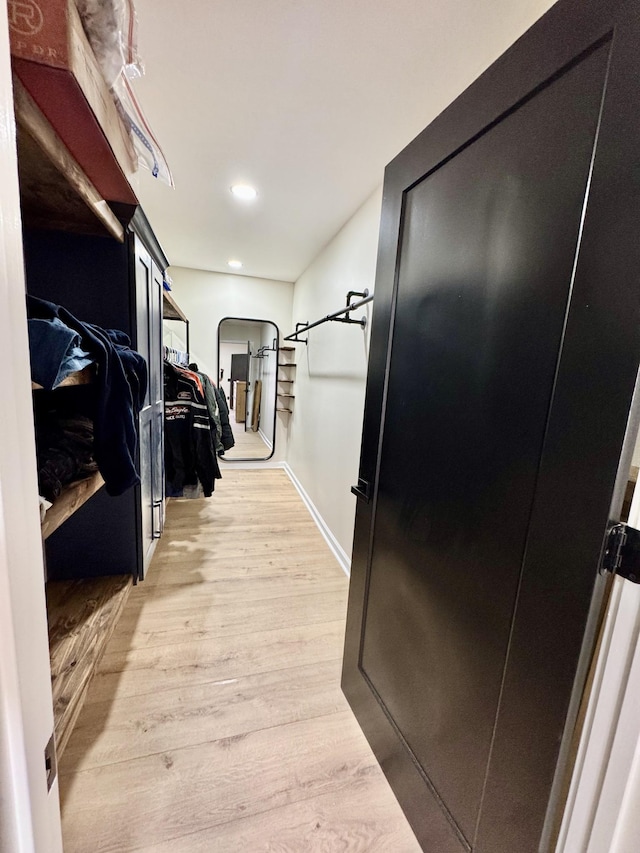 spacious closet with light wood-style floors and arched walkways