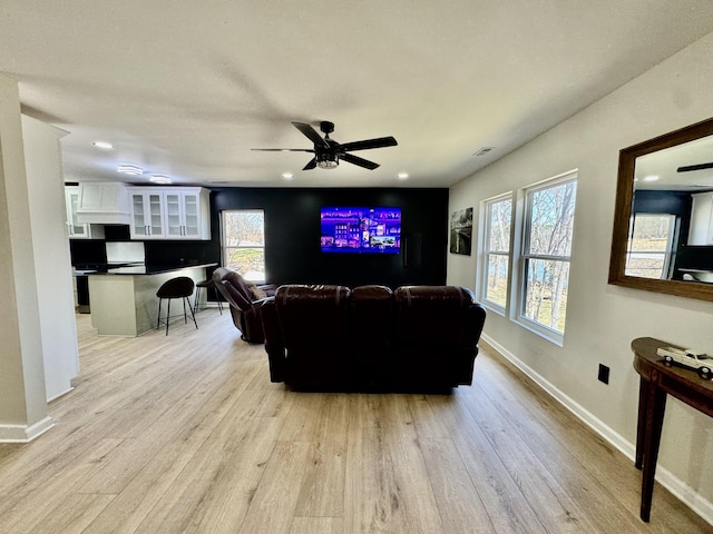 living room with baseboards, ceiling fan, visible vents, and light wood-style floors