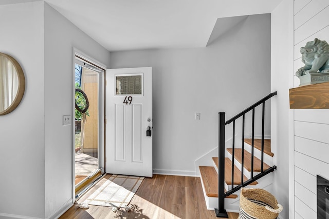 foyer entrance with stairs, baseboards, and wood finished floors