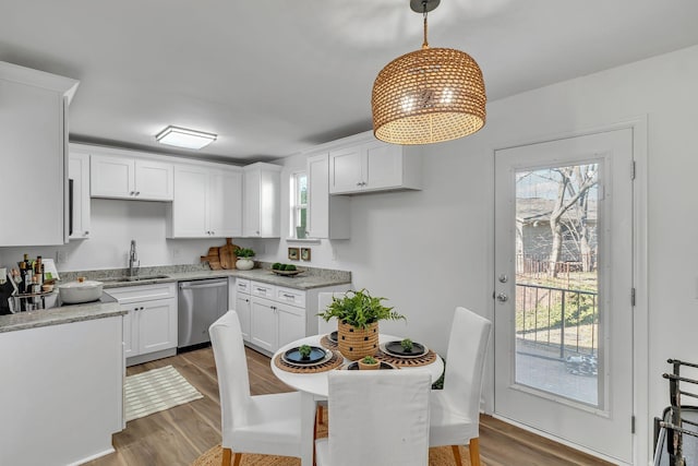 kitchen with a sink, white cabinets, stainless steel dishwasher, and wood finished floors