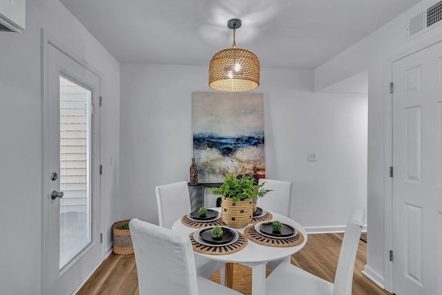 dining area featuring wood finished floors, visible vents, and baseboards