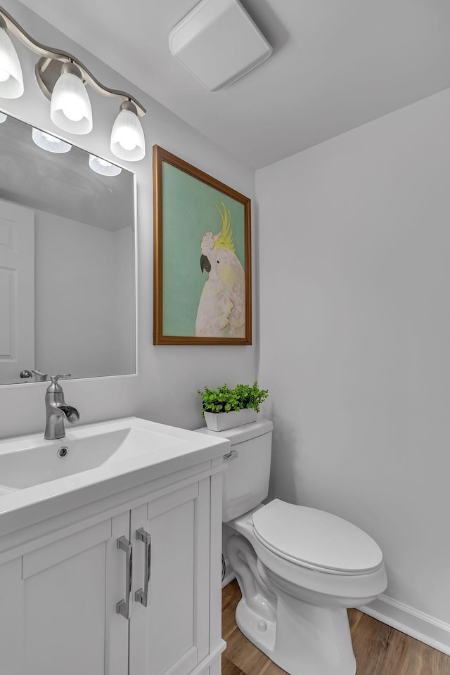 bathroom with toilet, baseboards, wood finished floors, and vanity