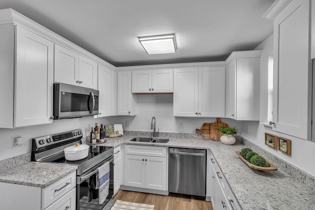 kitchen featuring stainless steel appliances, light wood-style floors, white cabinetry, and a sink