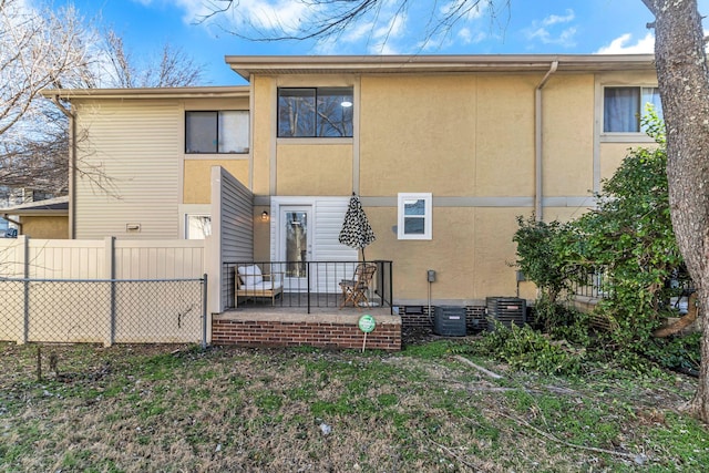 rear view of property with crawl space, fence, and stucco siding