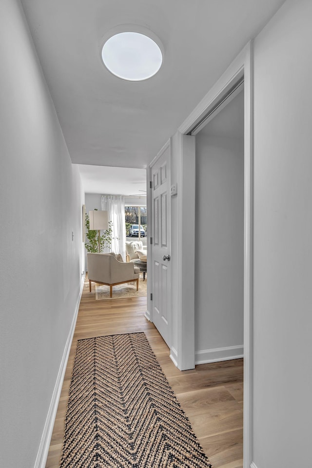 hall featuring light wood finished floors and baseboards