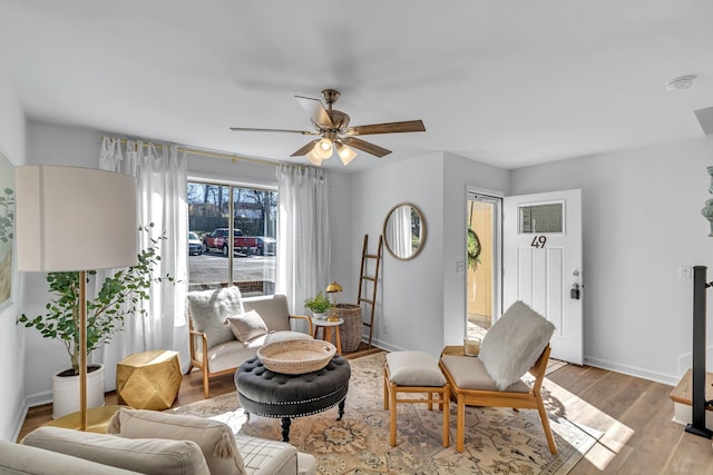 living area featuring light wood-type flooring, ceiling fan, and baseboards