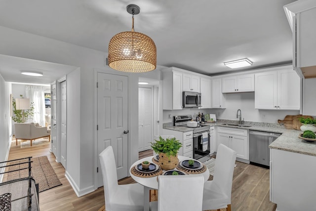 kitchen with light wood-style floors, white cabinetry, stainless steel appliances, and a sink