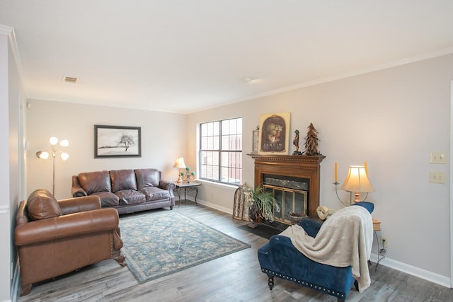 living area with crown molding, wood finished floors, a fireplace with flush hearth, and baseboards