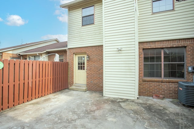 exterior space featuring central air condition unit, fence, a patio, and brick siding