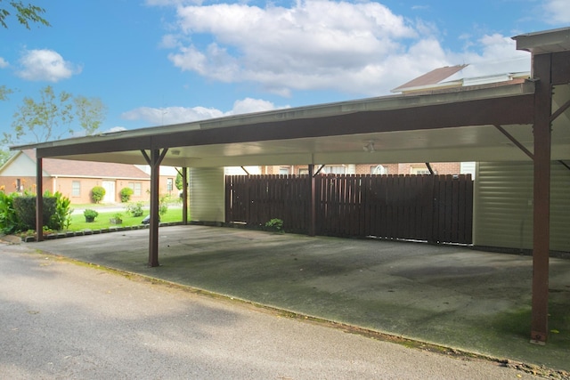 view of parking / parking lot with fence and an attached carport