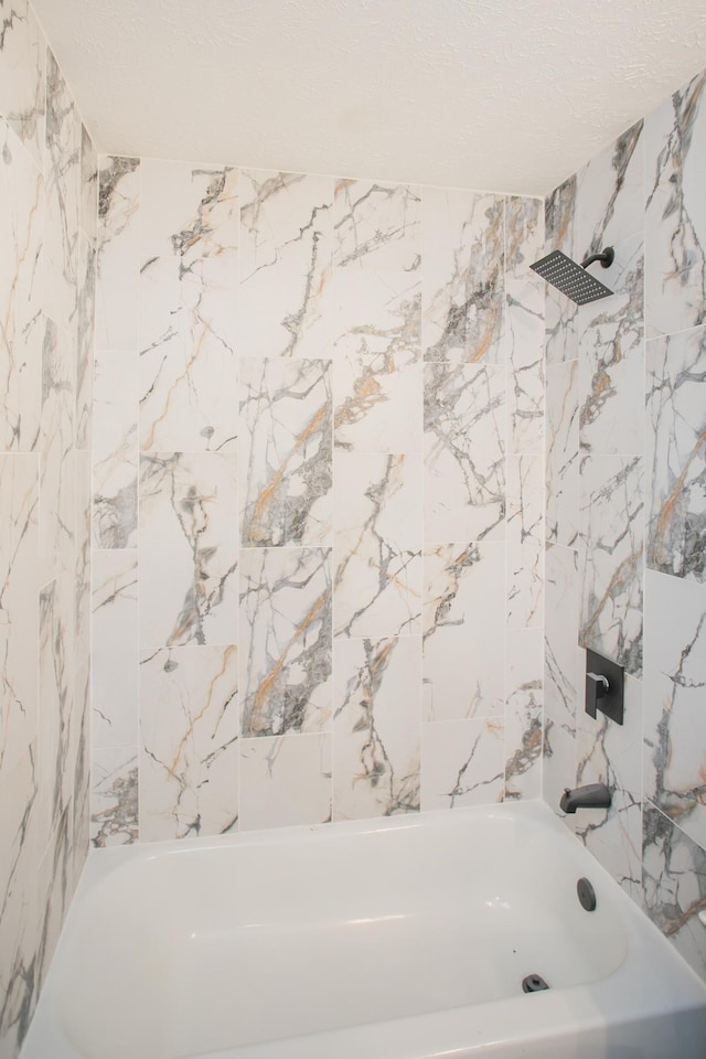 bathroom with shower / bath combination, a textured ceiling, and stone wall