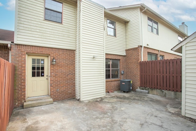 back of house with central AC unit, a patio area, fence, and brick siding