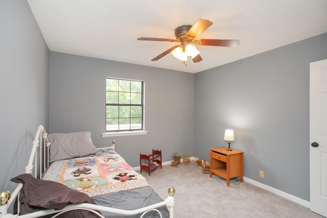 bedroom with a ceiling fan, light carpet, and baseboards