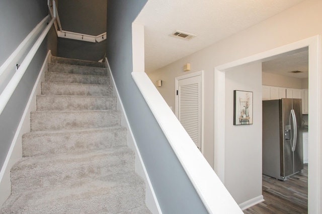 staircase featuring baseboards, visible vents, and wood finished floors