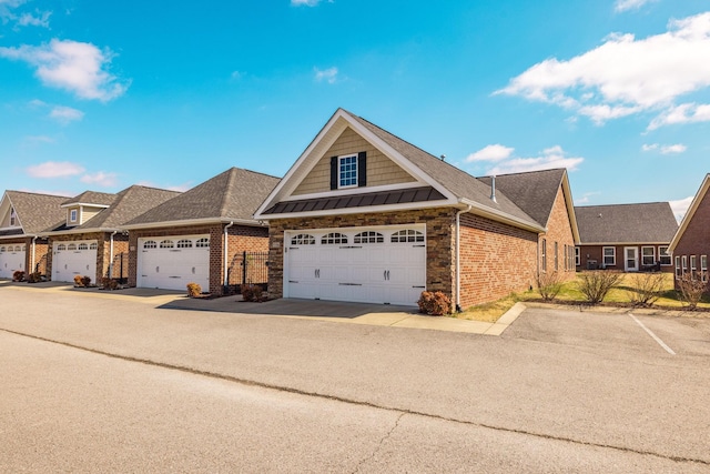 view of front of home with a garage, a standing seam roof, brick siding, and a shingled roof