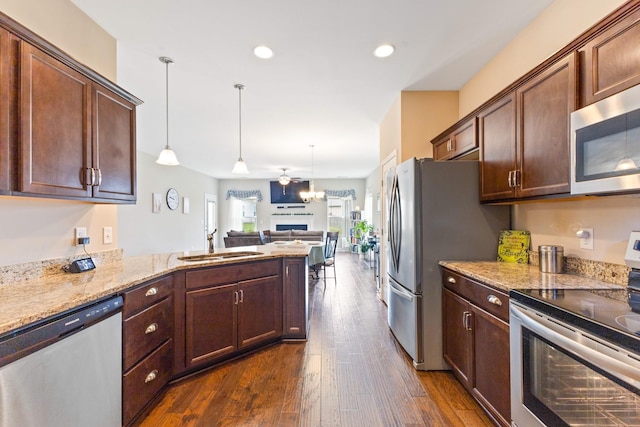 kitchen featuring dark wood-style floors, open floor plan, light stone countertops, stainless steel appliances, and a sink