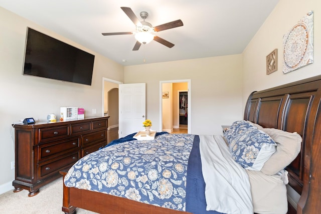 bedroom with arched walkways, ceiling fan, light colored carpet, baseboards, and a walk in closet