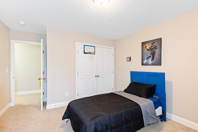 bedroom with light carpet, baseboards, and a closet