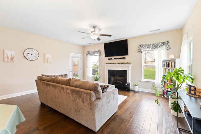 living room with a healthy amount of sunlight, baseboards, visible vents, and dark wood-type flooring