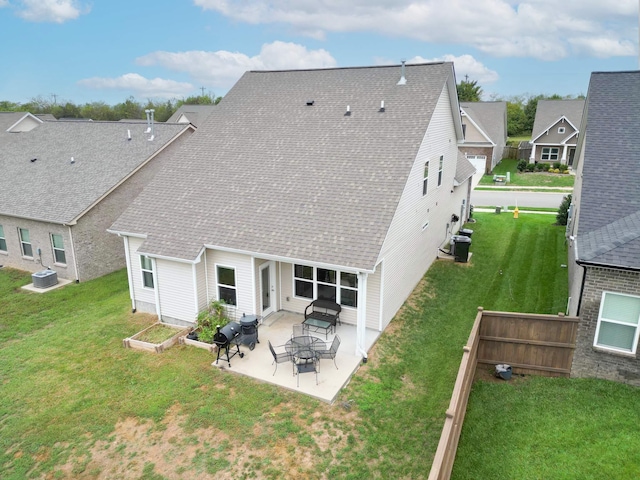 rear view of property with a shingled roof, a patio area, a yard, and central AC unit