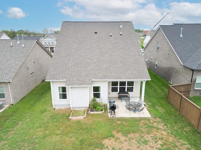 rear view of property with a yard, roof with shingles, fence, and a patio