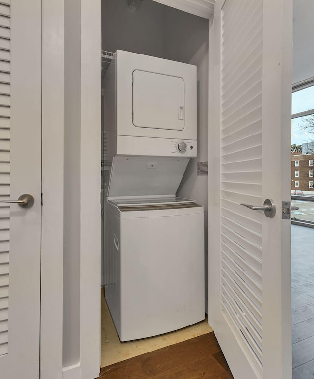 laundry area with laundry area, wood finished floors, and stacked washer and clothes dryer