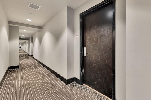 hall featuring baseboards, visible vents, and carpet flooring