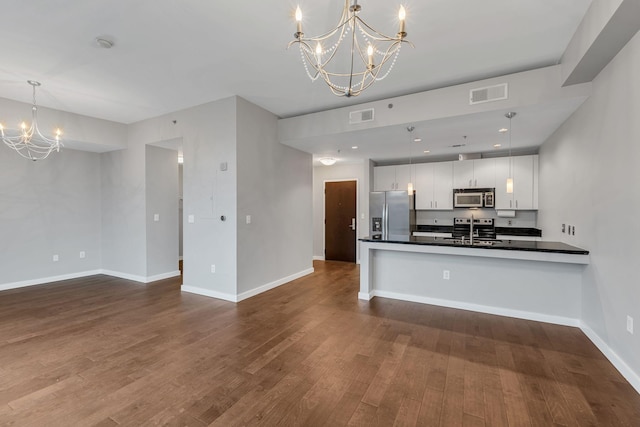 kitchen with a notable chandelier, stainless steel appliances, a sink, visible vents, and dark countertops