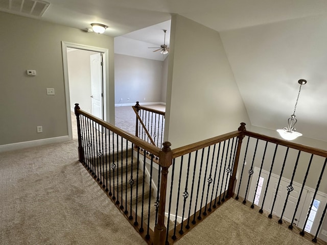 stairway featuring lofted ceiling, baseboards, visible vents, and carpet flooring