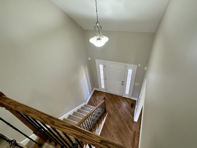 foyer featuring baseboards, a chandelier, dark wood-type flooring, stairs, and high vaulted ceiling