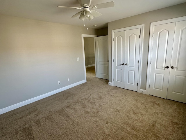 unfurnished bedroom featuring ceiling fan, baseboards, two closets, and carpet flooring