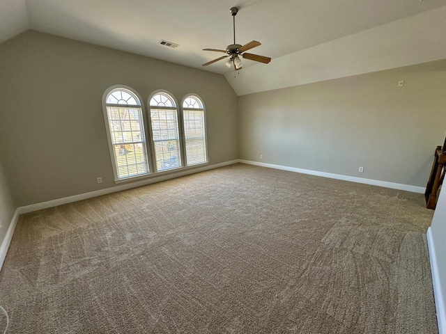 empty room featuring lofted ceiling, visible vents, baseboards, and a ceiling fan