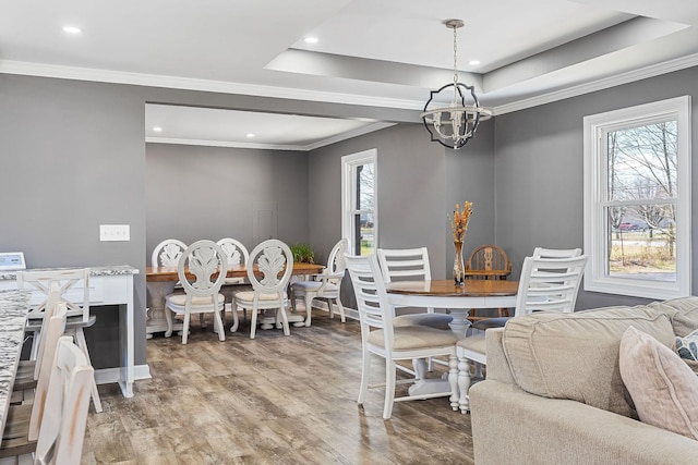 dining room with recessed lighting, a notable chandelier, wood finished floors, ornamental molding, and a tray ceiling