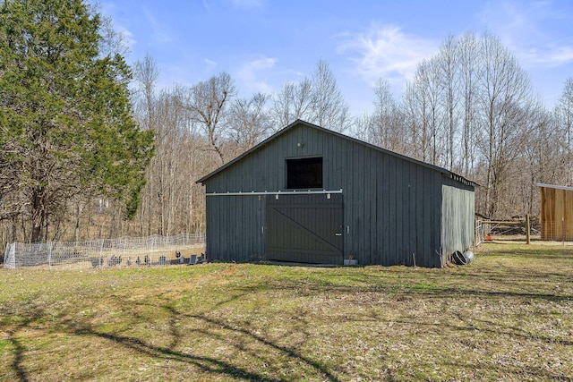 view of barn with a yard and fence