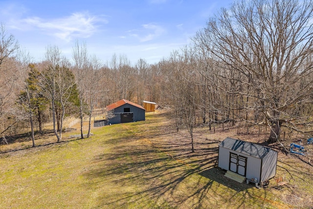 view of yard featuring an outbuilding, a pole building, and a view of trees