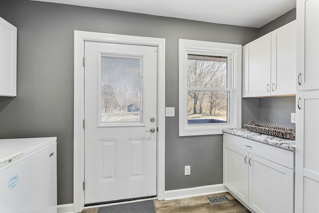 clothes washing area featuring wood finished floors, cabinet space, and baseboards