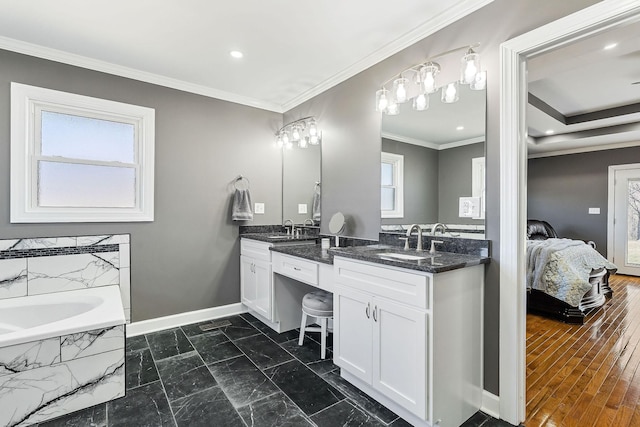 ensuite bathroom with double vanity, ornamental molding, a sink, and baseboards