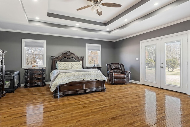 bedroom with baseboards, a raised ceiling, hardwood / wood-style floors, access to exterior, and french doors