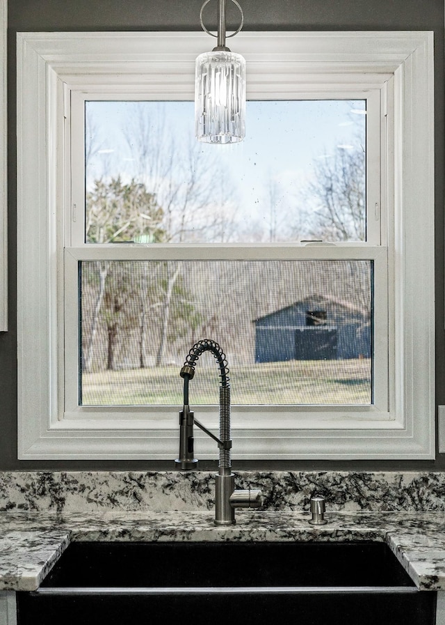 interior details featuring light stone countertops, a chandelier, white cabinets, and a sink