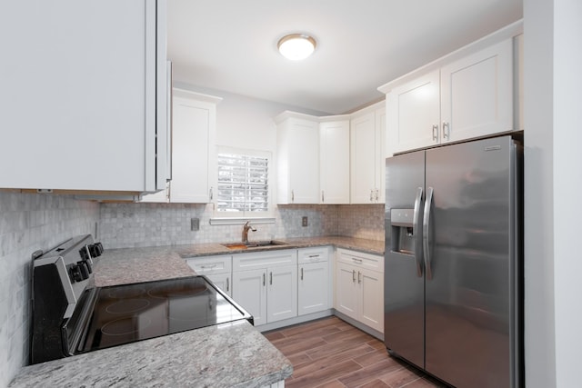 kitchen with decorative backsplash, appliances with stainless steel finishes, wood tiled floor, white cabinetry, and a sink